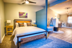 Image of a nicely laid out bed in a bed and breakfast in Nunavut. Room is modern and clean with ceiling fan and sufficient lighting. Space is cozy.