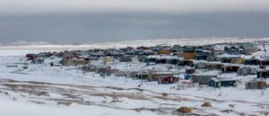 Sanikiluaq, a small community in Nunavut. Photograph taken during winter with windswept and exposed tundra in the foreground.