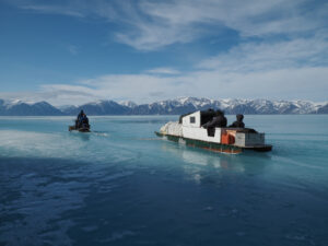 People on Skidoo towing a qamutik with people while on the ice in Nunavut.